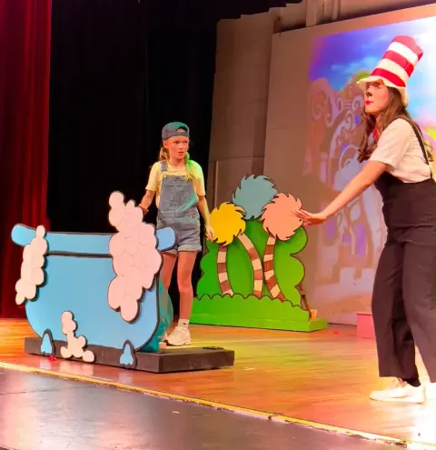 Two students playing a scene in front of the set